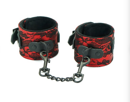A pair of red and black bondage handcuffs with a chain link connection